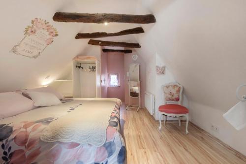 a bedroom with a bed and a red chair at La Perle Rosée in Azerat