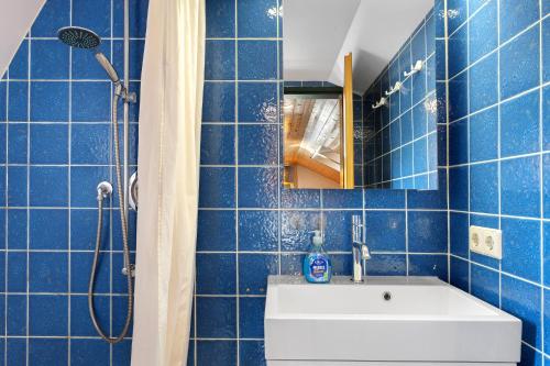 a blue tiled bathroom with a sink and a shower at Maisonette auf 1000m mit Sauna in Schönwald