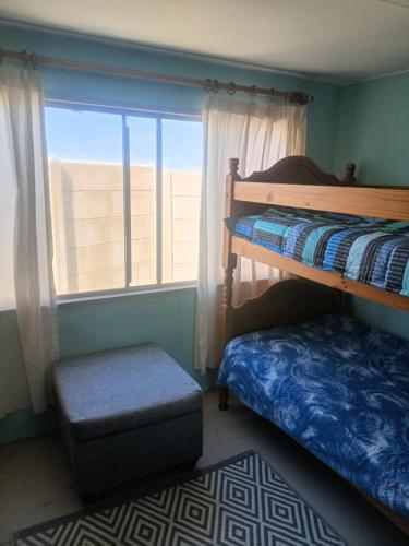a bedroom with two bunk beds and a window at Kaalvoet Kaia in Stilbaai-Oos