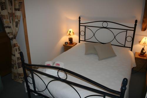 a bedroom with a bed with a black metal frame at Le Courtil De Bourrien in Languédias