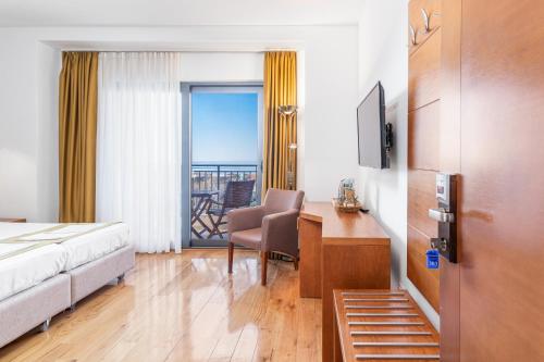 a hotel room with a bed and a desk and a balcony at Hotel Petrovac in Petrovac na Moru