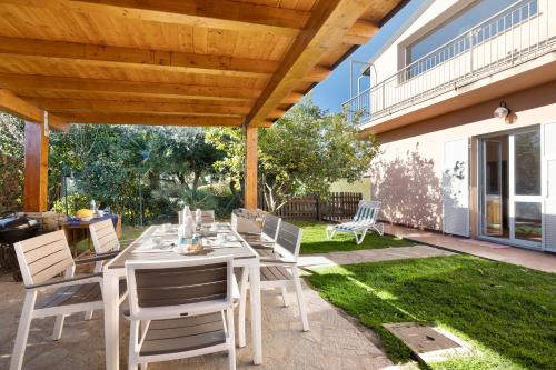 a patio with a table and chairs under a wooden pergola at Home Charlene parking e patio in Albenga