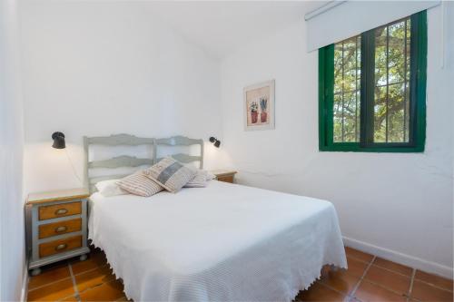 ein weißes Schlafzimmer mit einem Bett und einem Fenster in der Unterkunft Finca El Chopo - piscina compartida in Alájar