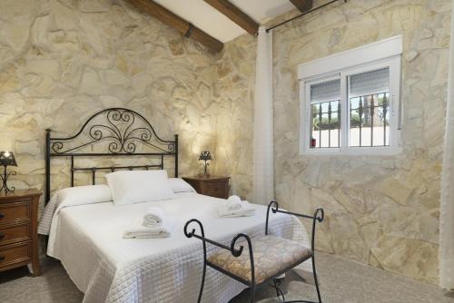a bedroom with a bed and a stone wall at Chalet Los Paul in Chiclana de la Frontera