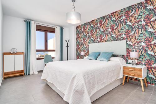 a bedroom with a large bed with a floral wallpaper at El ático del Oasis in Salobreña
