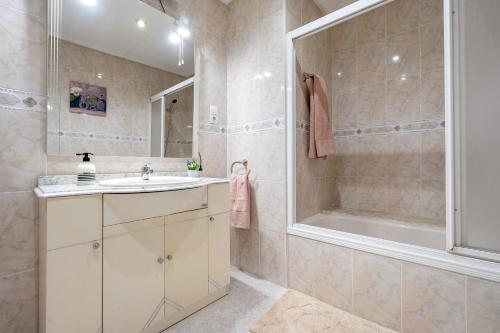 a bathroom with a sink and a shower and a tub at Apartamentos El Compromiso in Caspe