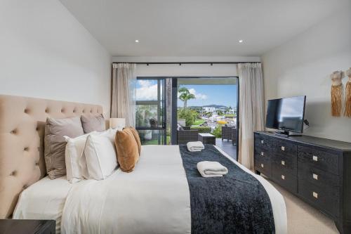 a bedroom with a large bed and a television at Villa One on the Waterways - Pool, Spa Pool, Tennis in Whitianga