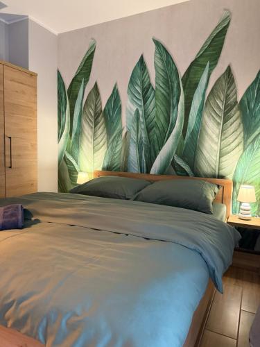 a bedroom with a mural of leaves on the wall at Kutnowska Perła in Kutno