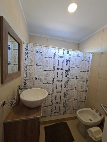a bathroom with a sink and a toilet and a shower curtain at El Portal Los Álamos in Rincon de los Sauces