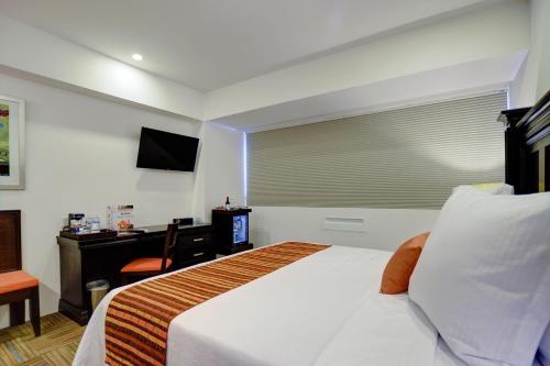 a bedroom with a bed with a desk and a window at Hotel Stadium Leon in León