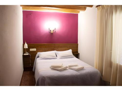 a bed with two white towels on it with a purple wall at Nogal in Hospital