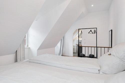 a white bedroom with a bed and a staircase at Historisches Forstamt in Gernsbach