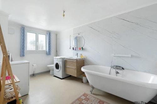 a white bathroom with a tub and a washing machine at Les Passiflores - Chambre d'Hôtes in Pornic