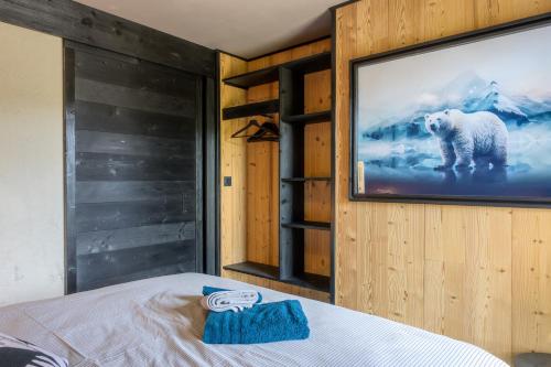 a bed in a room with a television on a wall at Le chalet Amélie in La Bresse