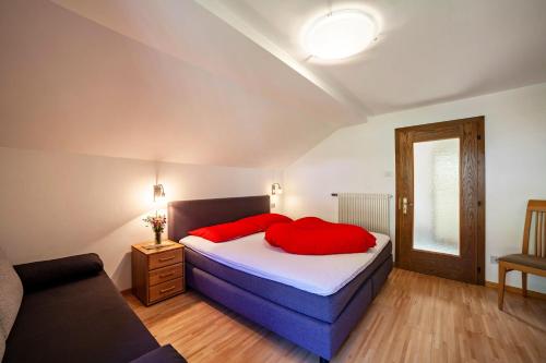 a bedroom with a bed with red pillows and a couch at Rieglhof Apartment Kükennest in Curon Venosta