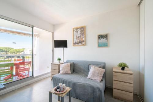 a living room with a blue couch and a window at Plage et Soleil Parking Privé Piscine Plage à 5 min in La Grande Motte