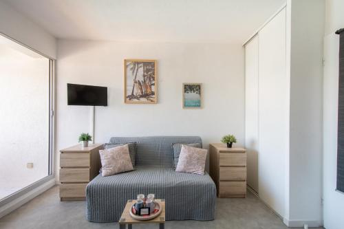 a living room with a couch and a tv at Plage et Soleil Parking Privé Piscine Plage à 5 min in La Grande Motte