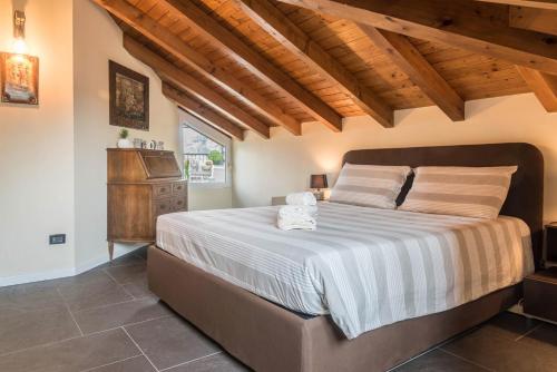 a bedroom with a large bed and a wooden ceiling at Maison Vittoria Lago Maggiore in Laveno-Mombello