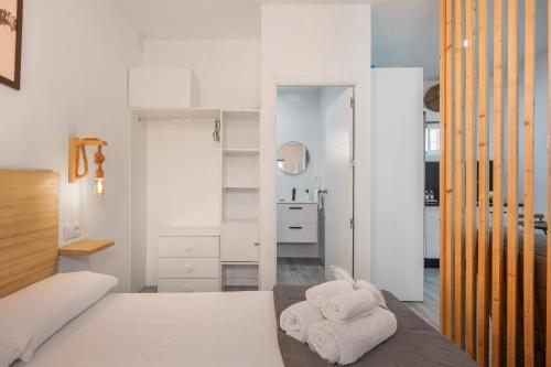 a bedroom with white walls and a bed with towels at Casa Abuela Maria in Jerez