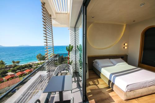 a bedroom with a bed and a balcony with the ocean at Coral Boutique Hotel in Vlorë