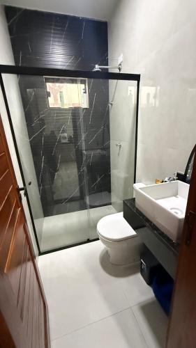 a bathroom with a glass shower and a toilet and a sink at Casa em tibau in Tibau