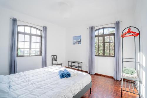a bedroom with a white bed and two windows at Casa das 3 Marias in Biscoito Bravo