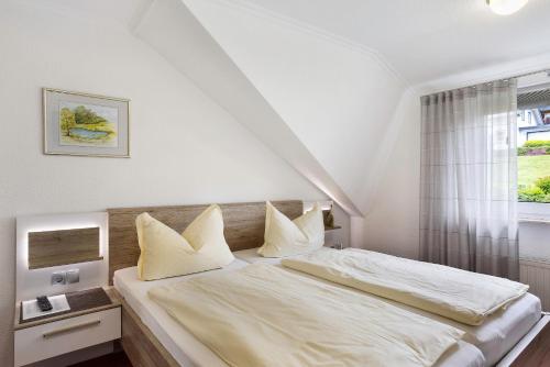 a bedroom with a bed with white sheets and pillows at Ferienwohnung Becker in Schwalefeld
