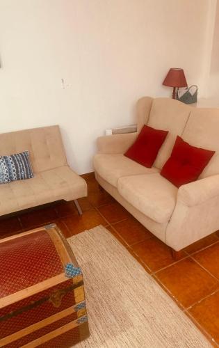 a living room with a white couch and red pillows at Casa Jubileu in Golegã