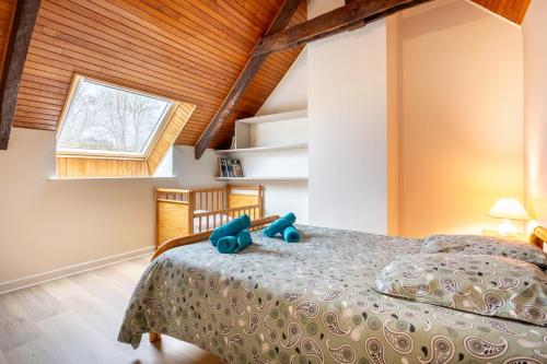 a bedroom with a bed with a blue teddy bear on it at La longère familiale et authentique in Melgven