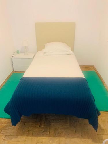 a bed with a blue and white blanket on the floor at Casa Jubileu in Golegã