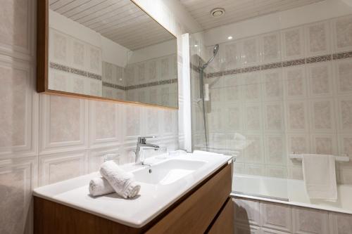 a white bathroom with a sink and a shower at Hôtel de la Pointe du Grouin in Cancale