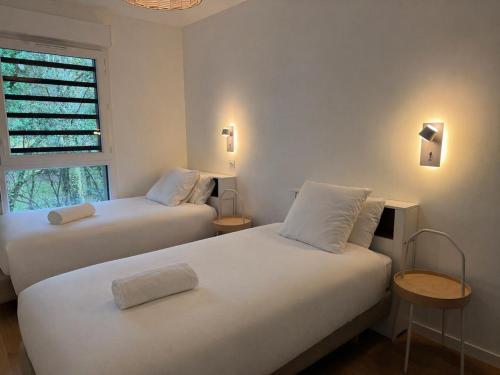 two beds in a room with a window at Appartement Autza 6 voyageurs proche des plages in Moliets-et-Maa