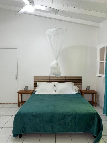 a bedroom with a green bed with two tables at Studio La Marguerite - Vue mer avec terrasse privée - calme tropical à Deshaies in Deshaies