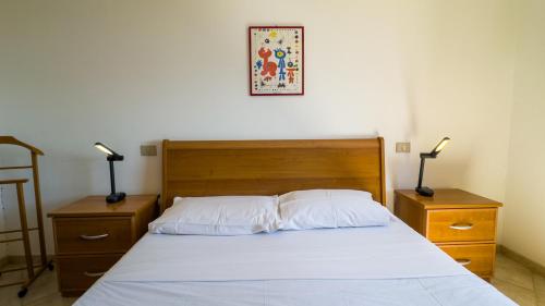 a bedroom with a bed with two night stands and two lamps at Blue Horizon Sinis in Funtana Meiga