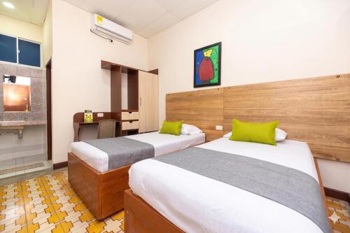 a hotel room with two beds and a desk at Hotel Skal Inn in Barranquilla