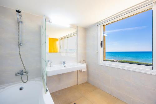a bathroom with a tub and a sink and a window at Villa Bella Ena in Nea Dimmata