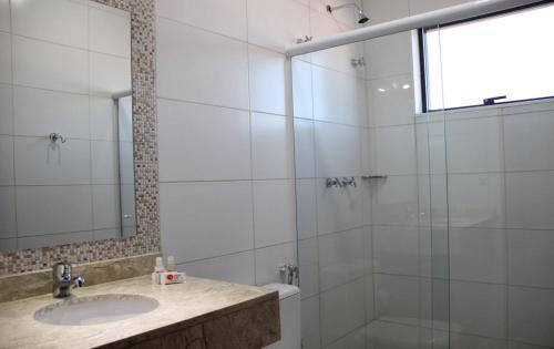 a bathroom with a sink and a glass shower at Estância Avaré Hotel in Avaré