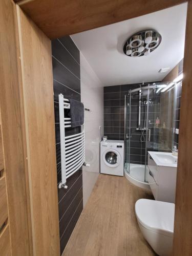 a bathroom with a sink and a washing machine at Apartament Arbuzowy Zachód Słońca in Pobierowo