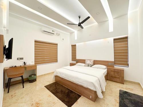 a bedroom with a bed and a desk and a ceiling fan at CRK Home Stays in Cochin