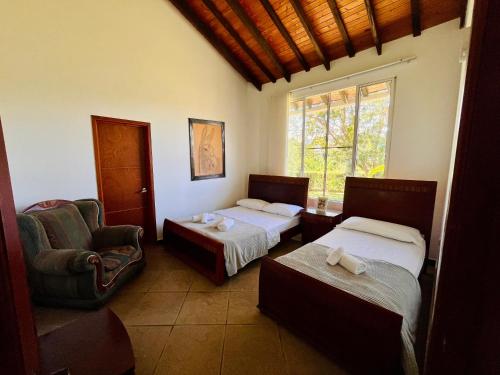 a hotel room with two beds and a chair at Villa Edén Alto in La Tebaida