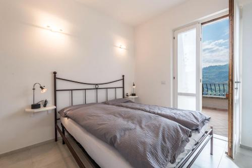 a bedroom with a bed and a large window at Comfort Appartamento Le Cementine in Tremosine Sul Garda