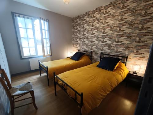 two beds in a room with a brick wall at Gîte de Lonzanges in Lanobre