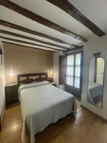 a bedroom with a large bed and a mirror at Hostal Rey Pedro I in Santo Domingo de la Calzada