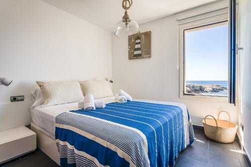 a bedroom with a bed with a blue and white blanket at Binibeca Sunset in Sant Lluis