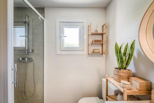 a bathroom with a shower and a toilet with a plant at Binibeca Sunset in Sant Lluis