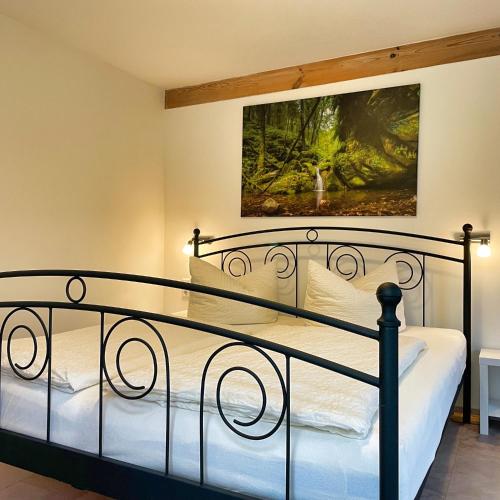 a bedroom with a metal bed with a painting on the wall at Ferienhaus Gipfelblick im Sandsteinidyll in Rathen