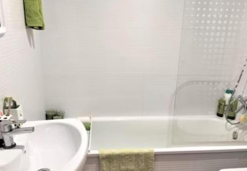 a white bathroom with a tub and a sink at Duplex Mediterranea in Benicarló