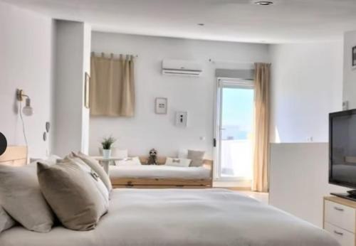 a white bedroom with a bed and a television at Duplex Mediterranea in Benicarló
