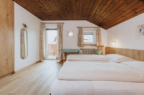 two beds in a bedroom with a wooden ceiling at Unterhauserhof App B in Valdaora