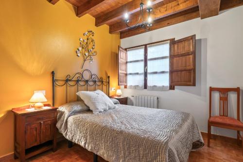 a bedroom with a bed and a chair and a window at Orandi in Cangas de Onís